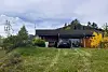 Eit hus i eit grønt tun med parkert bil og gule buskar.
