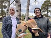 To personar står utandørs med blomsterbukettar.