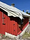 Raudt naust med kvitt tak og blå himmel.