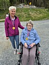 To kvinner med medaljar, éi i rullestol og éi ståande ved ein grusveg.