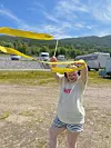 Person held opp gul banderoll ute med fjell og bilar i bakgrunnen.