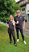 To personar står ute framfor eit bygg og held opp små kvite produkt.