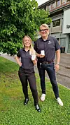To personar står ute framfor eit bygg og held opp små kvite produkt.