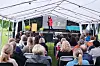 Publikum under telt ser ein person på scena framføre eit innslag.