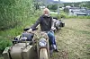 Mann sit på motorsykkel med sidevogn på ein grasbakke.
