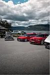 Bilar står parkert på ein asfaltplass ved fjorden.
