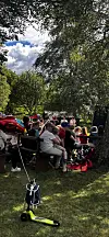 Folk sit samla i ein park, med sparkesykkel i framgrunnen.