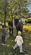 Tre barn og ein vaksen står ved ein hest under eit tre.