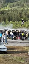 Motorsyklist hoppar over bil framfor ein folkemengd.