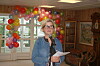 Kvinne talar med mikrofon framfor fargerike ballongar.