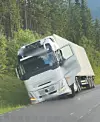 Kvit lastebil står skeivt ved vegen i skogsområde.