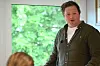 Mann står innandørs ved eit vindauge.