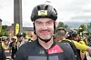 Syklist i hjelm står framme, med fleire syklistar samla bak i startområdet.