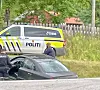 Politiet står ved ein svart bil, med ein politibil parkert bak.