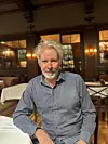 Ein mann sit ved eit bord inne på ein restaurant.