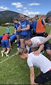 Fotballspelarar står og bøyer seg på ei grasbane.