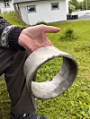 Ei hand held ein slitt metallring over gras.