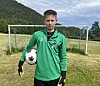 Ung fotballspelar med ball framfor eit mål på grasbane.