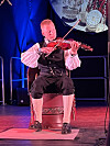 Fiolinist sit på scena og spelar, med blå og raud scenelys.
