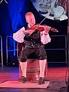 Fiolinist sit på scena og spelar, med blå og raud scenelys.