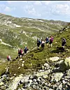 Turgåarar går over ein steinete fjellskrent i fjellet.