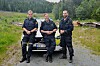 F.v. Marin Omholt, Erik Wågene og Henrik Andersson står framfor ein politibil ute i skogsterreng.