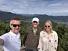 Tre personar står ute med fjord og fjell i bakgrunnen.