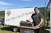 Ein mann står ved ein motor på ein tilhengar utandørs.