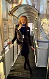 Kvinne i mørk uniform står på glasoverbygd gangbru.
