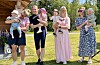 Sju vaksne står på ein plen og held fire små born framfor seg.