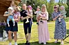 Sju vaksne står på ein plen og held fire små born framfor seg.