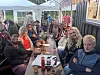 Folk sit rundt eit bord under telt ved ein serveringsstad.