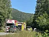 Utrykkingskøyretøy står langs ein veg med skog og fjell i bakgrunnen.