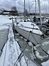 Seglbåt ligg fortøygd ved ei islagt bryggje med snø og is rundt.