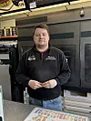 Mann står ved ein disk i butikkinteriør.
