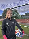 Målvakt i svart treningstøy står ved fotballmål med ein ball.