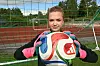 Ung fotballspelar med ball framfor eit mål på kunstgrasbane.