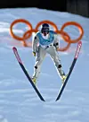 Jan Rune Grave svevar nedover i hoppbakken med olympiske ringar i bakgrunnen.