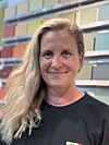 Kvinne står framfor ei vegg med fargeprøver og ser mot kamera.