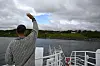 Person på ferjedekk vinkar mot land.
