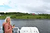 Kvinne på dekk held mobiltelefon ved fjorden.