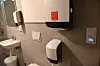 Toalettrom med dispensarar, vask og veggpanel.