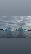 To isfjell flyt på havet under skydekt himmel.