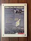Informasjonstavle om villrein med tekst, kart og bilete av reinsdyr på trevegg.