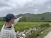 Person i caps peikar mot fjell og grasmark.