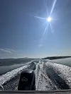 Båtsett bakfrå med kjølvasspor på fjorden under sola.