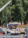 Person heisar ein sykkel med kran ved ei brygge.