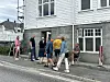 Ei gruppe personar samlast utanfor eit hus i ei bustadgate.