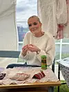 Kvinne sit ved bord og trer smykke i eit telt.