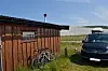 To syklar ved eit trenaust og ein mørk varebil på graset.